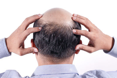 Rear view of man with hands on head against white background