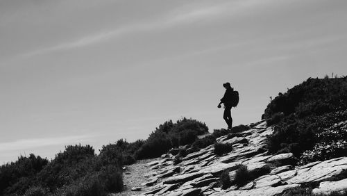 Low angle view of silhouette man on rock against sky