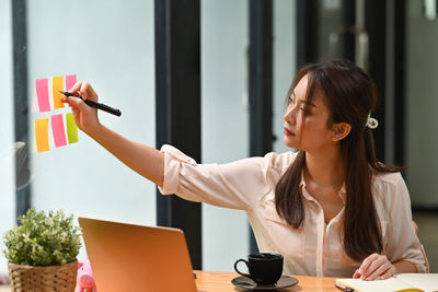 Young woman using phone while sitting on table