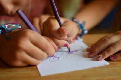 Close-up of siblings drawing in paper on table