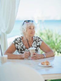 Attractive senior woman sitting in a summer outdoor cafe