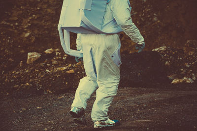 Low section of person in astronaut costume walking on field