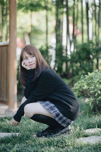 Full length of young woman squatting over grass