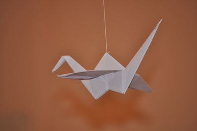 Close-up of origami hanging against orange wall