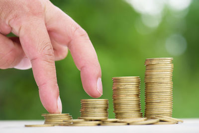 Cropped hand climbing coins stacked on table