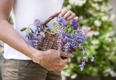 Midsection of woman holding flowering plant in pot