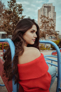 Beautiful young woman sitting on outdoor play equipment at playground