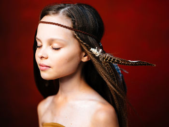 Portrait of beautiful young woman against red background