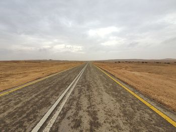 Road amidst field against sky