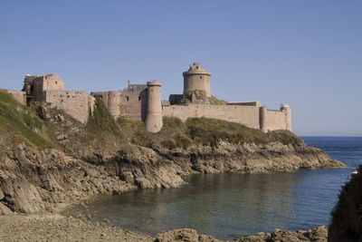 Castle by sea against clear sky