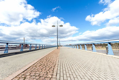 Empty walkway against cloudy sky