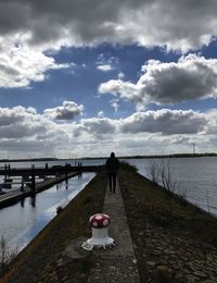 Man on pier over sea against sky