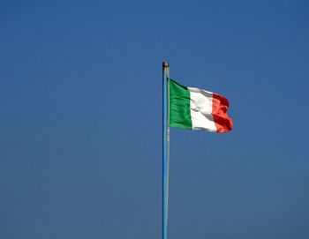 Low angle view of flag against blue sky