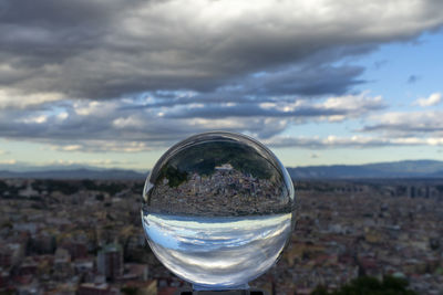 Close-up of crystal ball on glass against sky