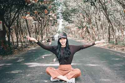 Portrait of young woman standing against tree