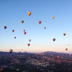 Hot air balloons flying above landscape against blue sky