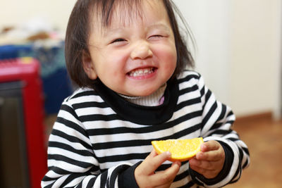 Cute girl holding lemon slice at home