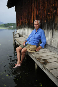 Portrait of smiling senior man sitting on jetty in summer