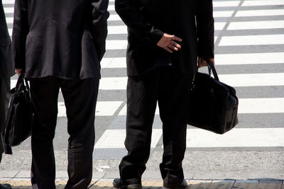 Low section of business people with luggage on road