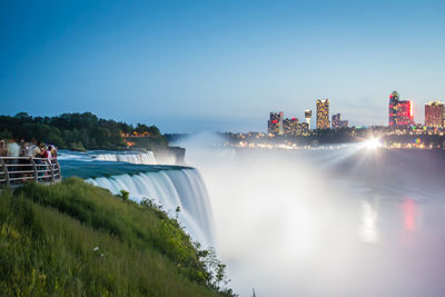 Long exposure of waterfall with city buildings seen in background