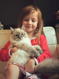 Portrait of cute girl with dog sitting at home