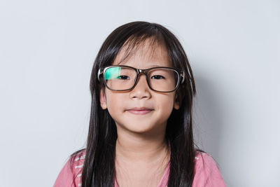 Portrait of girl wearing eyeglasses against white background