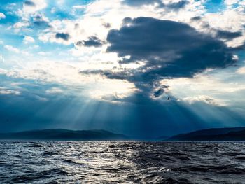 Sunlight streaming through clouds over sea