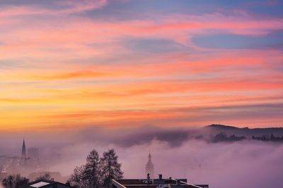 Silhouette of city against cloudy sky during sunset