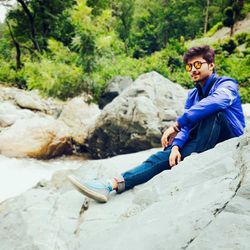 Portrait of smiling young man sitting on rock