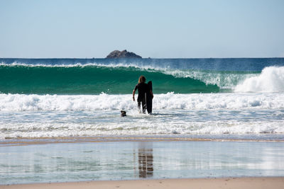 Rear view of men on beach against clear sky