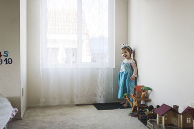 Girl standing against window at home