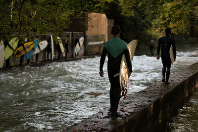 Rear view of surfers walking over lake