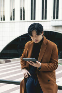Asian man outside the business center, using looks at his tablet