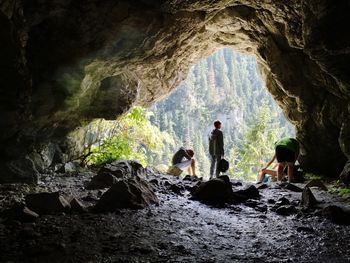 People relaxing on entrance of cave