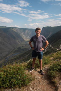 Full length of young man standing on mountain against sky