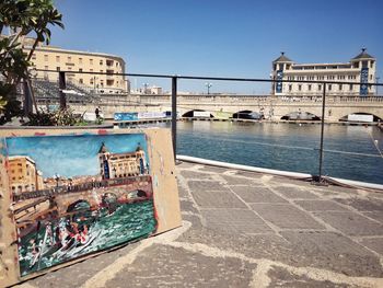 Painting on promenade by river against sky