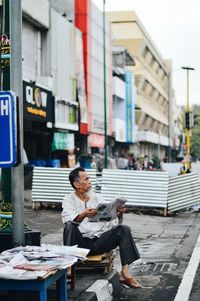 Man sitting on table against buildings in city