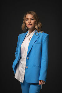 Portrait of young man standing against black background