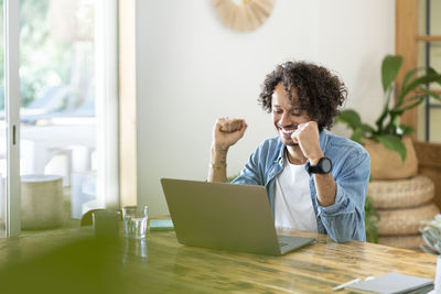 Young woman using phone while sitting on table