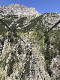 Rear view of person on footbridge against mountains