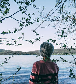 Rear view of woman looking at lake against sky