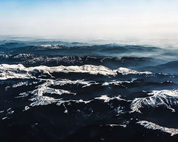 Aerial view of sea and snowcapped mountains against sky