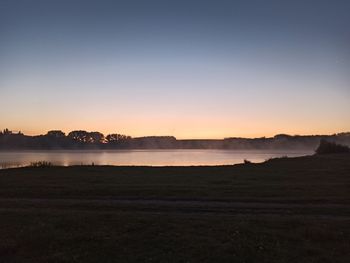 Scenic view of lake against clear sky during sunset