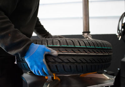 Midsection of mechanic holding tire at garage