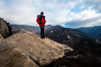 Man standing on rock against sky