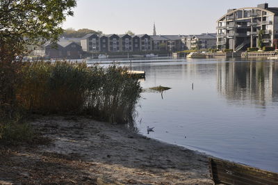 Buildings by lake against sky in city