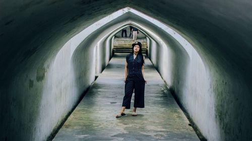 Rear view of woman walking on footpath in tunnel