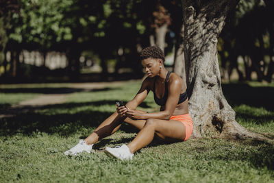 Young woman sitting on tree trunk in field