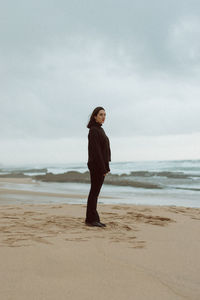 Full length of woman standing on beach against sky