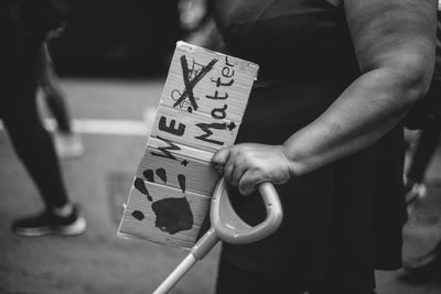 Midsection of man holding placard on street